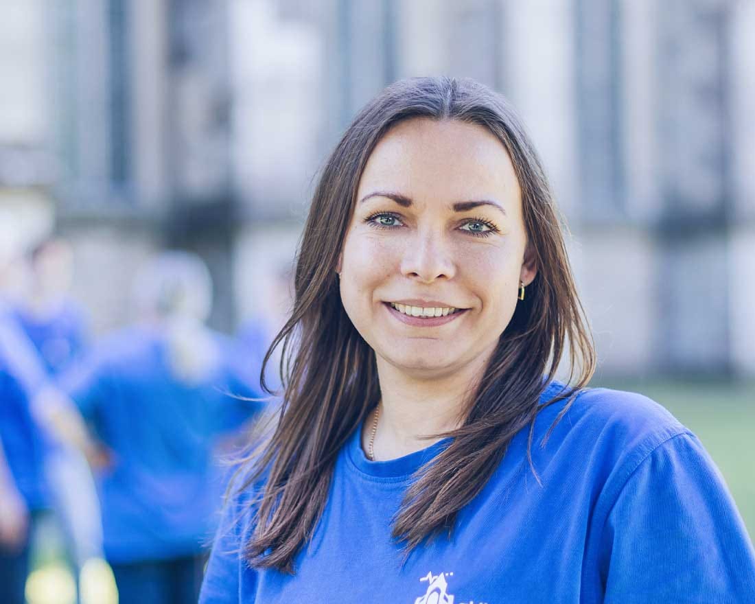 Lächelnde Mitarbeiterin der Aktiv Pflege Odenthal im blauen Team-Shirt